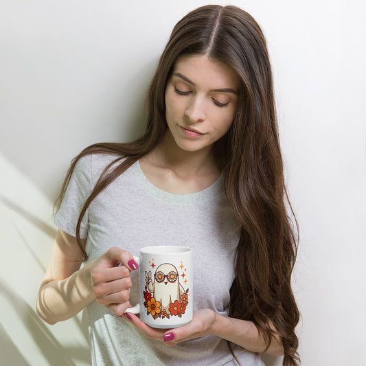 Mujer tomando una bebida en una taza blanca con diseño de fantasma floral de Halloween