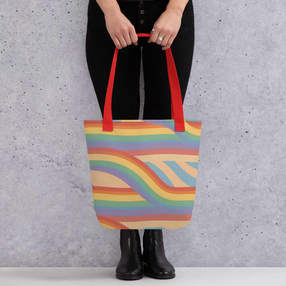 Modelo vistiendo ropa oscura y llevando al hombro la bolsa de tela de ondas multicolor retro con asas en color rojo.