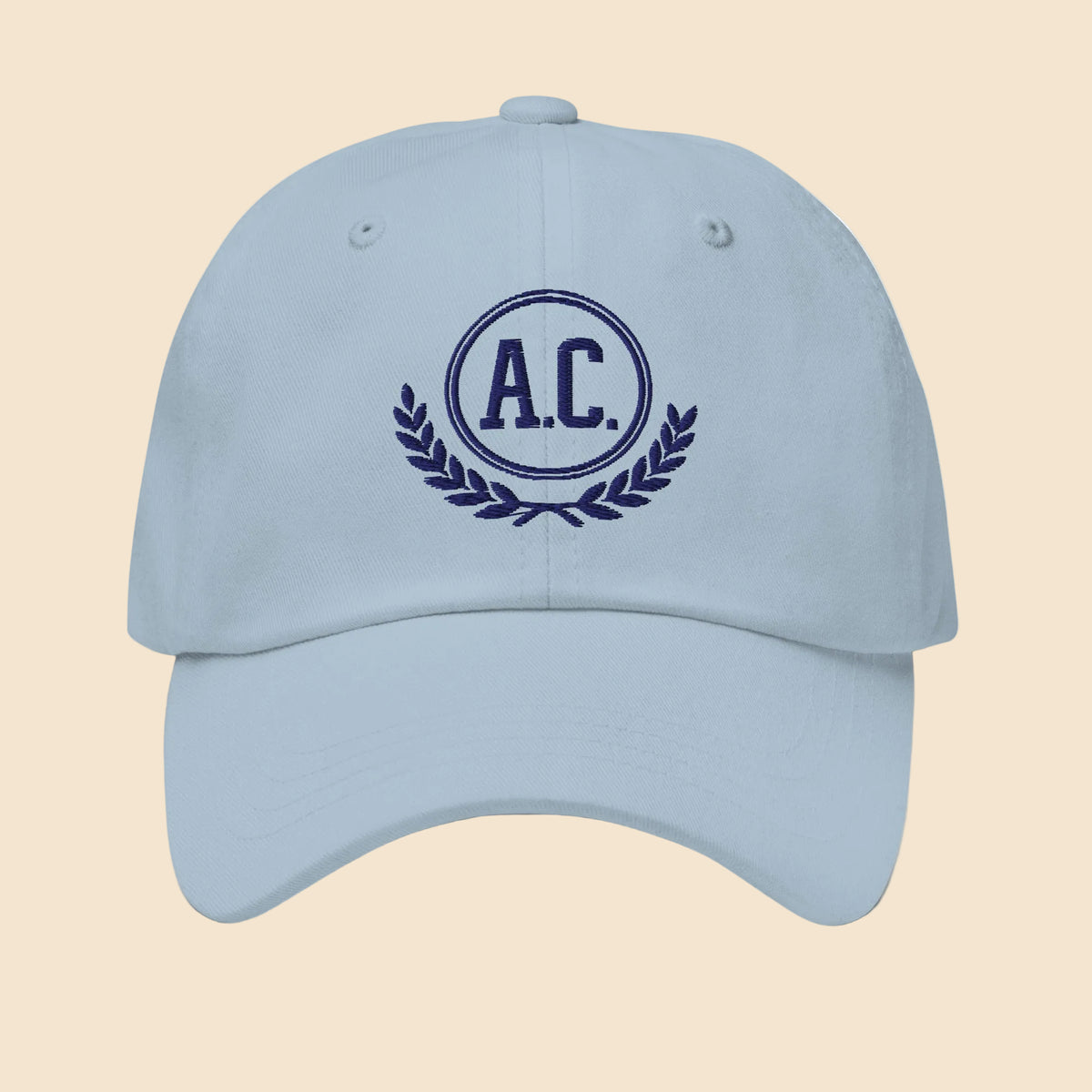 Gorra dad hat unisex en color azul claro con bordado frontal clásico de estilo universitario A.C. y laurel.