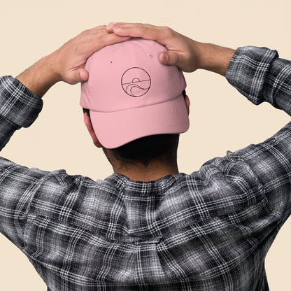 Hombre de espaldas con camisa de cuadros luciendo la gorra dad hat rosa, mostrando el cierre ajustable.