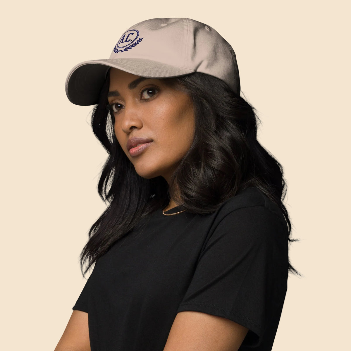 Mujer de perfil vistiendo gorra de béisbol color piedra de perfil bajo y diseño universitario.