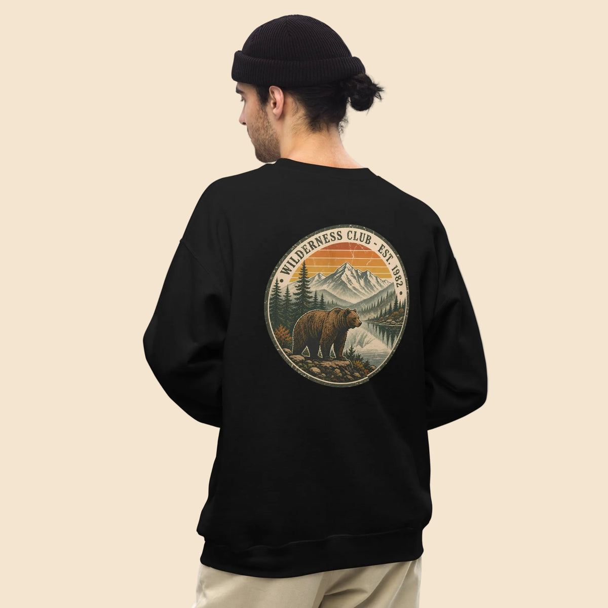 Hombre vistiendo sudadera negra cuello redondo con diseño vintage de naturaleza y oso pardo
