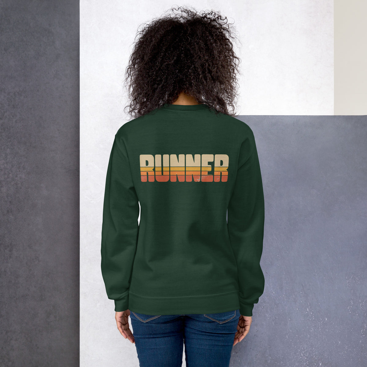 Mujer de espaldas vistiendo sudadera verde bosque con gráfica Runner clásica.
