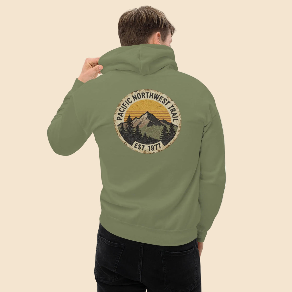 Hombre de espaldas vistiendo sudadera verde outdoor con gráfico de senderismo.