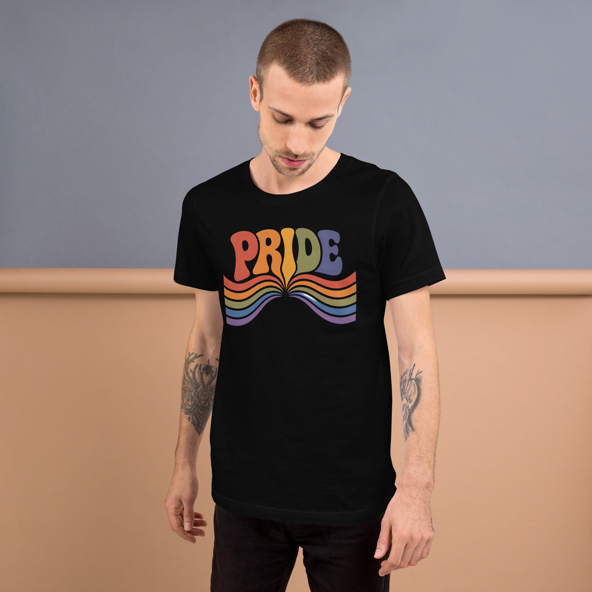 Hombre vistiendo camiseta de manga corta negra con ilustración psicodélica y colores de la bandera arcoíris.